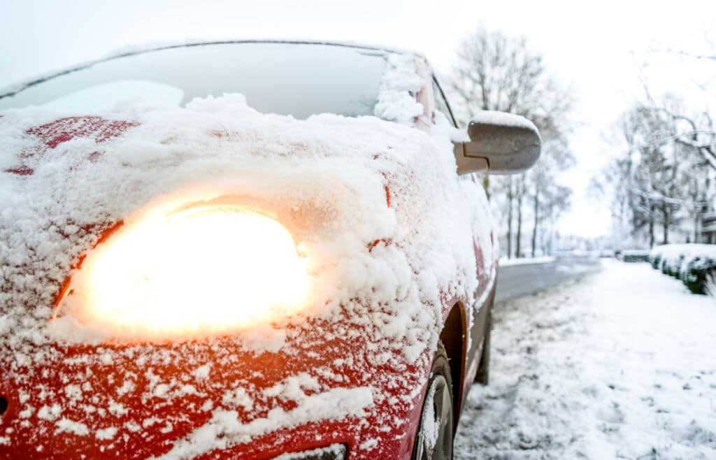 Red car with tire in snow on the side of the road | Marietta Wrecker Service